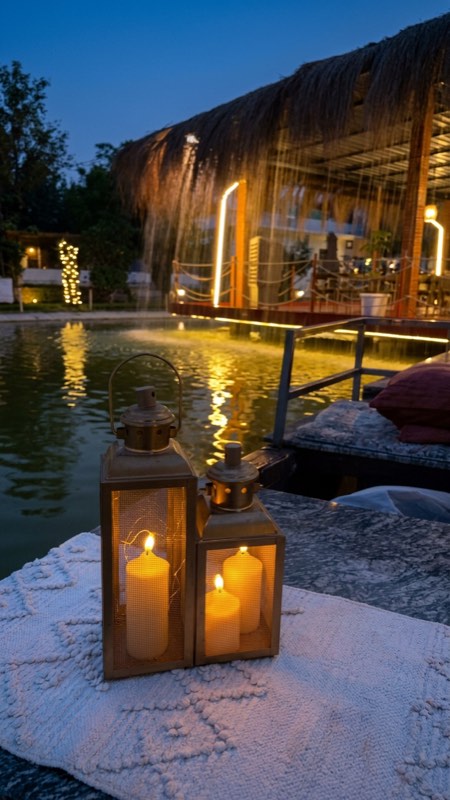 Candle lanterns at dusk beside the glowing lakeside café